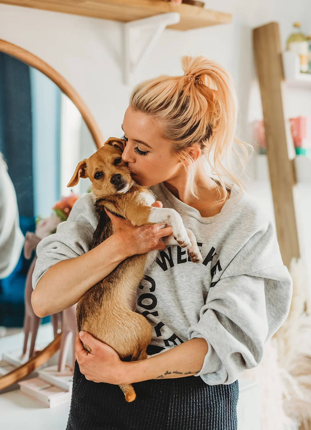 woman tenderly kissing jack russell chihuahaha puppy on the head